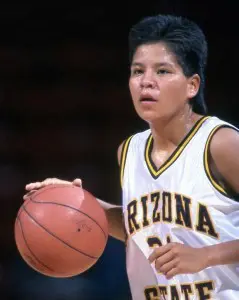 A young girl holding onto a basketball on the court