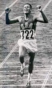 A man running on the track in an old photo.