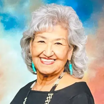 A woman with white hair and blue jewelry.