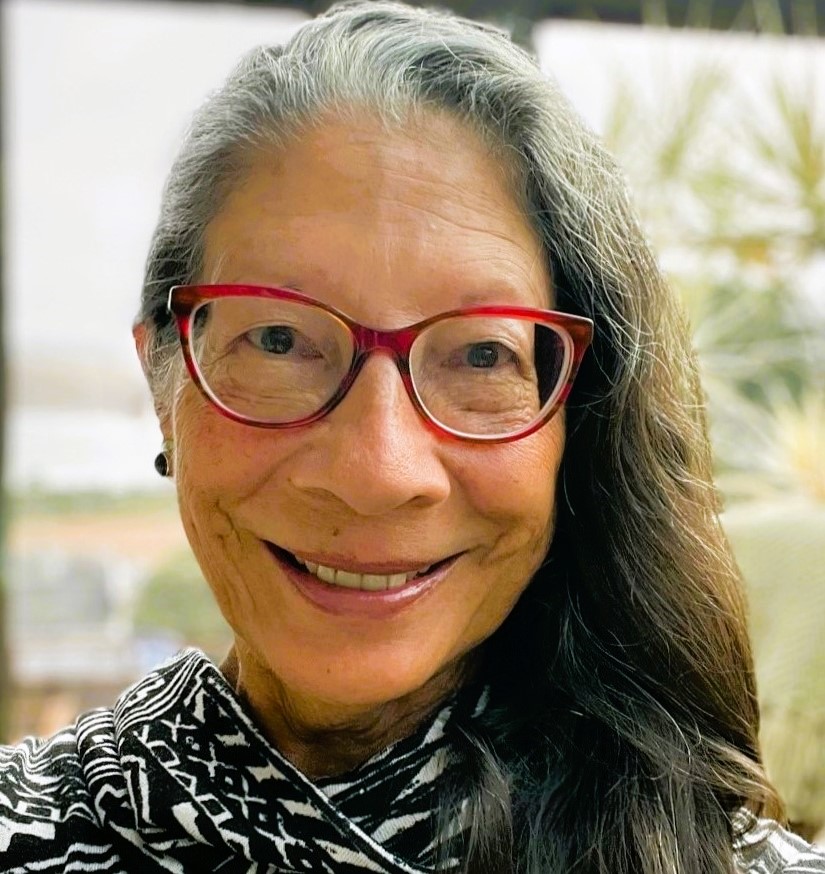 A woman with long hair wearing glasses and smiling.