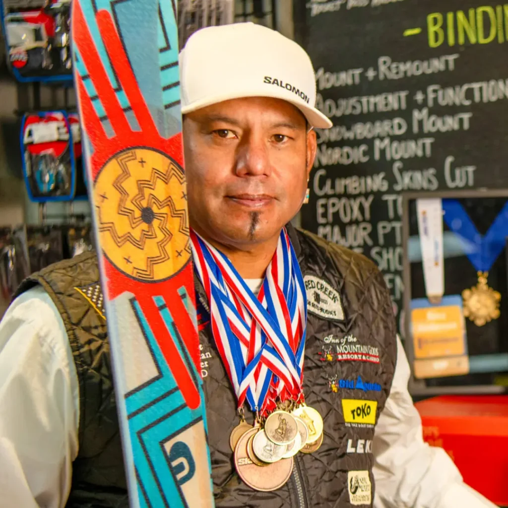 Man with medals holding colorful ski.