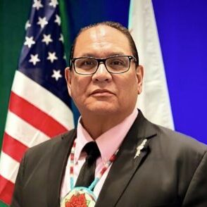 Man in suit with medallion and U.S. flag